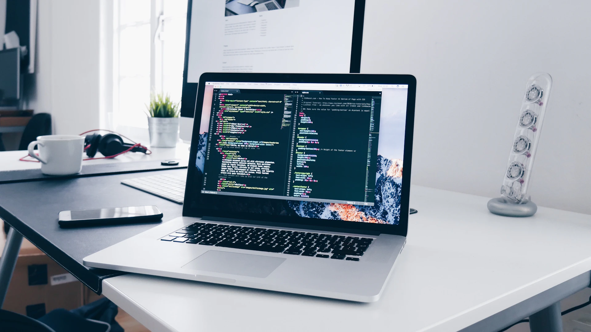 Laptop with lines of code on a busy developer desk