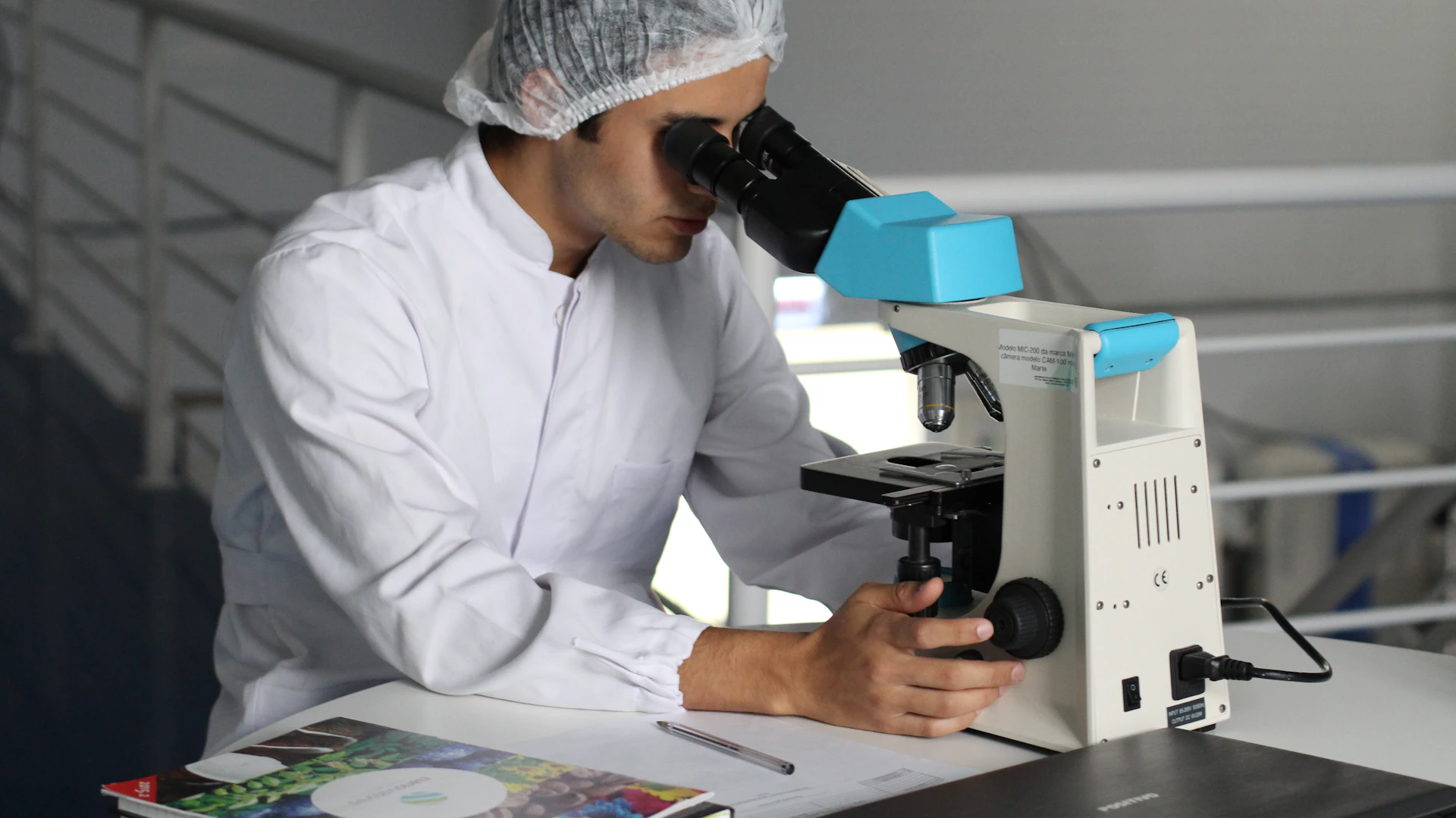 Scientist looking through a white microscope