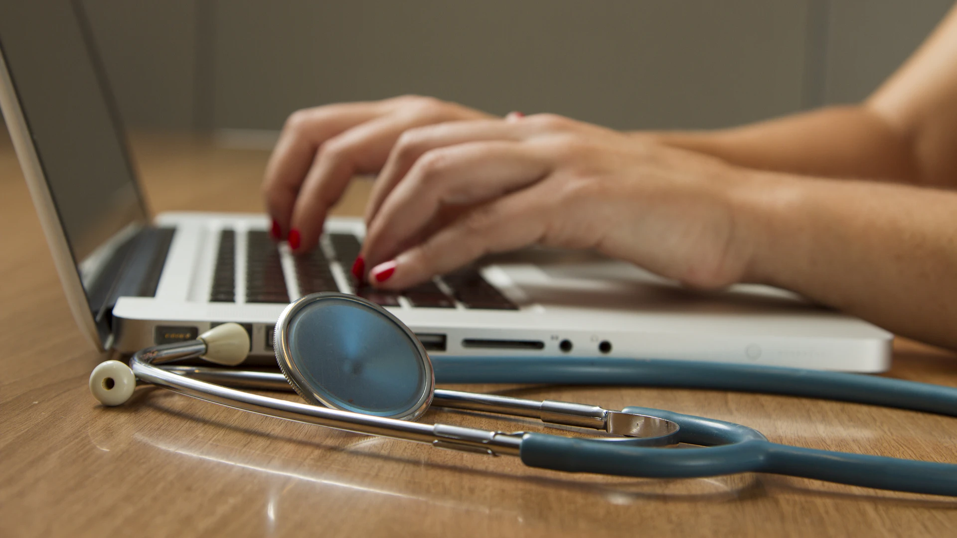 Doctor using a laptop with a stethoscope nearby
